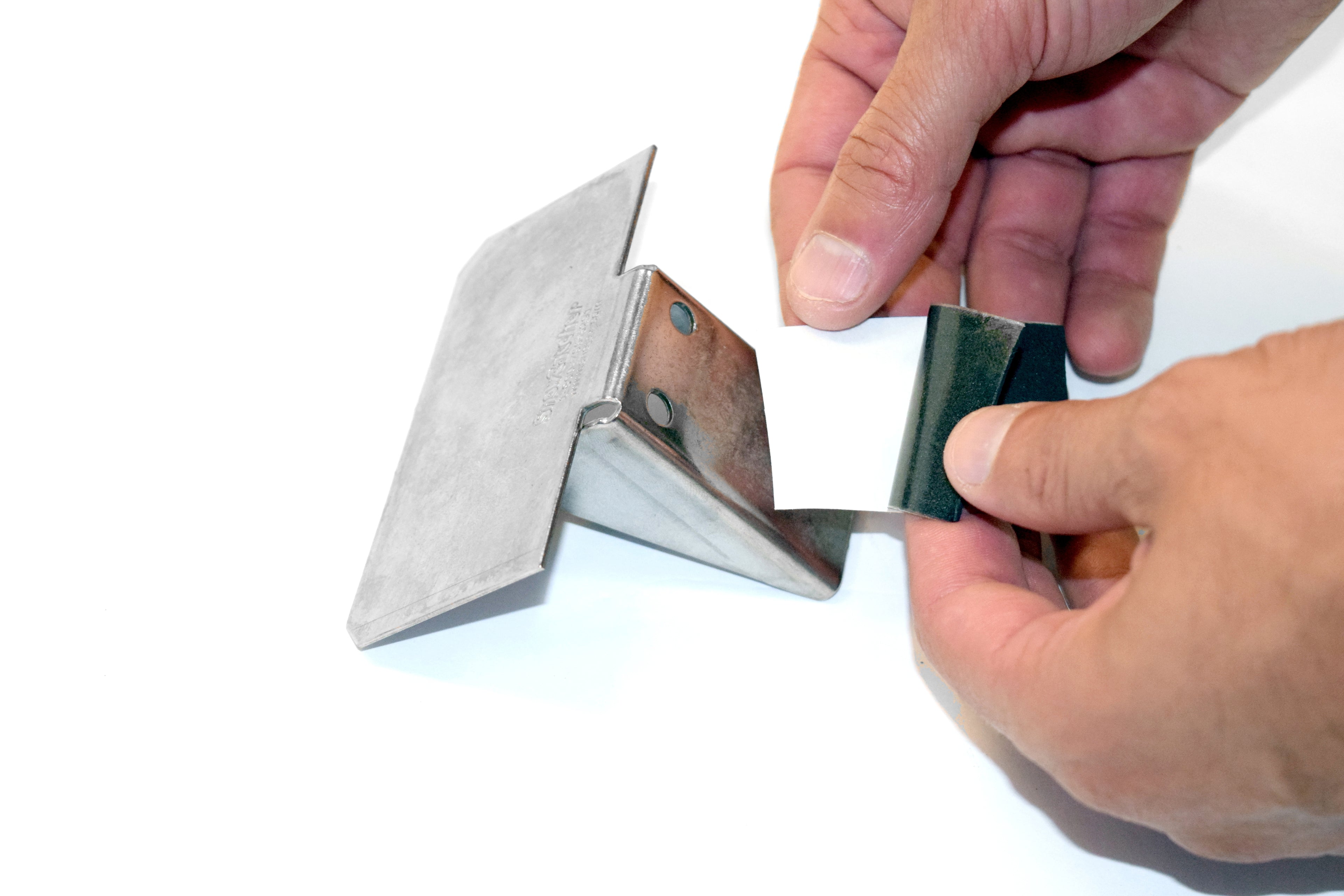 Applying gasket tape to the base of a SnowCatchers stainless steel snow guard before installation
